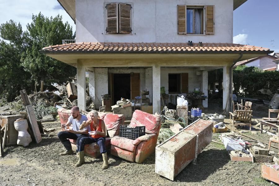 Una coppia si concede una pausa mentre recupera i propri effetti personali nella casa devastata dall'alluvione.    PhotoAnsa 2022 - Un anno di eventi in mostra